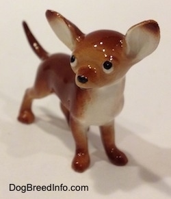 A brown with white Chihuahua figurine. The figurine has a black circle for a nose.